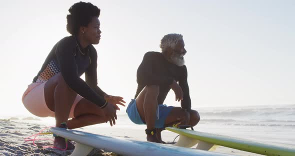 Happy african american couple with surfboards on sunny beach