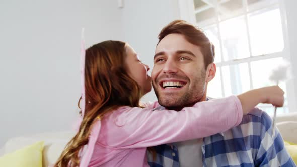 Girl dressed up in a fairy costume embracing her father