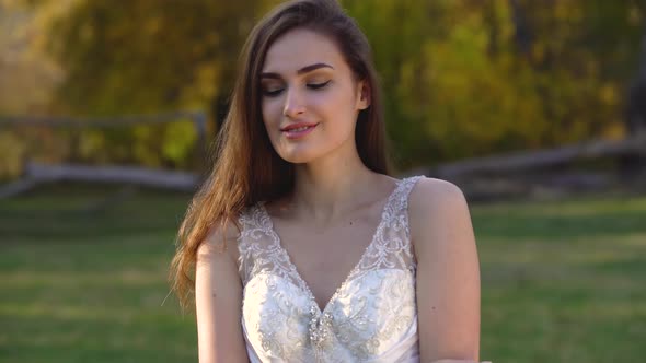 Portrait of Beautiful Brunette Woman with Long Hair Is Posing in Sunny Rays at Autumn Park