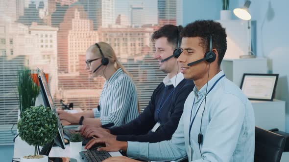 Portrait of Smiling Mixed-race Man Taking Call in Busy Call Center