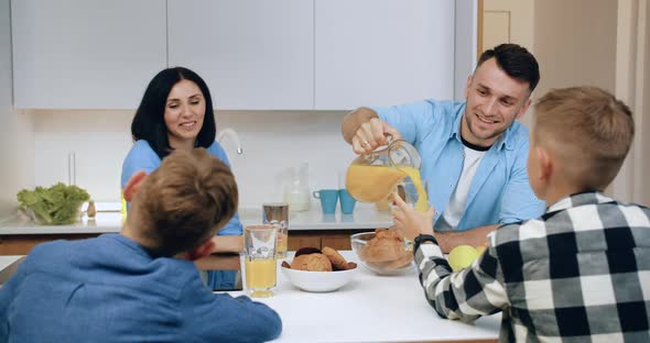 Happy Smiling Carefree Family Sitting at Dinner Table in Cuisine and Has Breakfast