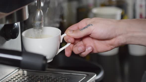 Tattooed Barista Pouring Hot Water into Cup to Make Americano