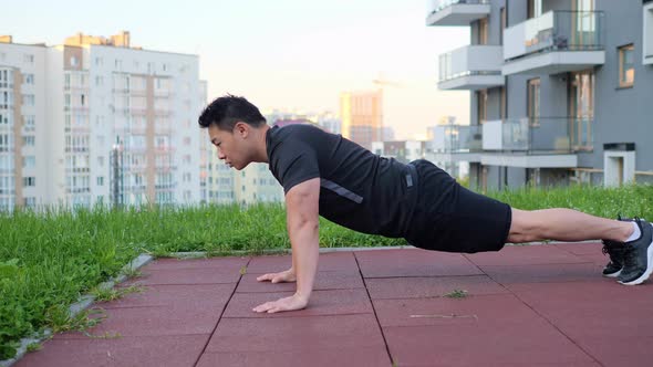 Portrait of Male Doing Pushup Exercise on Sports Ground in Sleeping Area Town