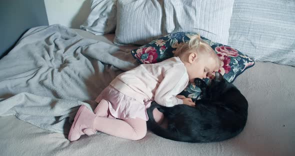 Little toddler girl is sleeping with black cat on living room