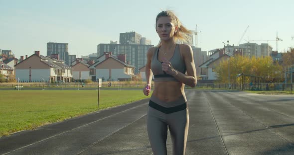 Woman Running at a Stadium in Sunny Day.