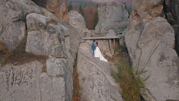 Newlyweds Stand on a High Slope of the Mountain, Groom and Bride, Arial View