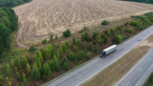 Cars Drive on Fourlane Highway Stretching Between Fields