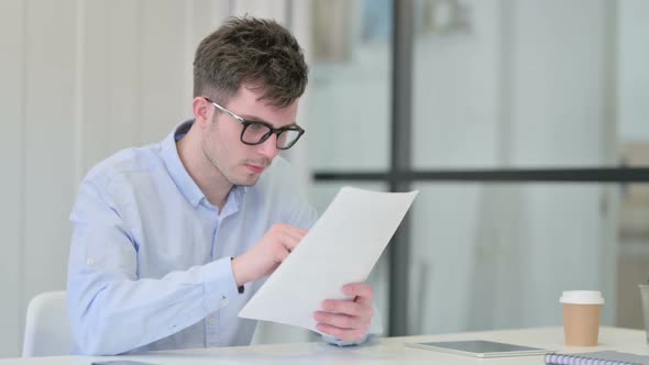 Young Man Celebrating Success on Documents