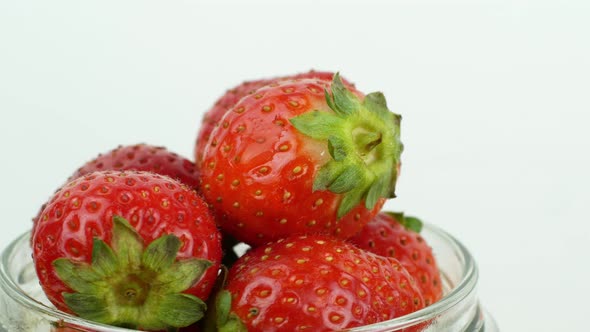 4K glass jar with red ripe strawberries rotating on a white background. Ripe summer red strawberry