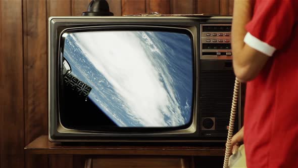 Man watching a Hurricane from Space on a Retro TV.