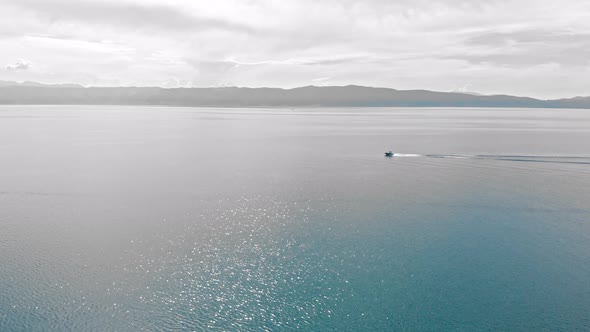 Aerial shot of a boat moving on turquoise water around Macedonian Ohrid Lake in Southern Europe.