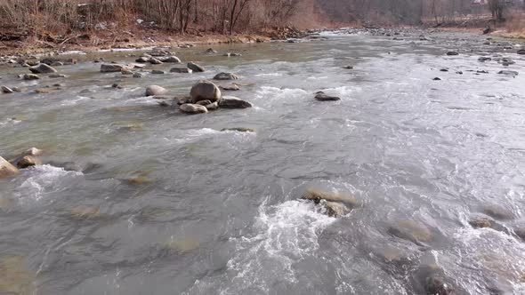 Flying Over Wild Mountain River Flowing with Stone Boulders and Rapids