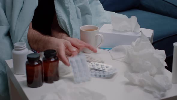 Close Up of Ill Man Looking at Capsule Tablets on Table