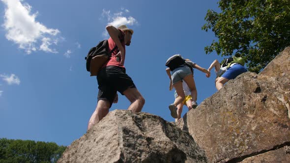 Hikers Helping To Friends To Climb on Mountain Top