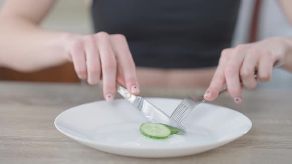 Female Hands Cutting Cucumber Slice with Knife and Fork