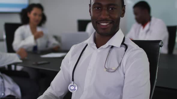 Portrait of african american male doctor sitting in meeting room looking to camera smiling