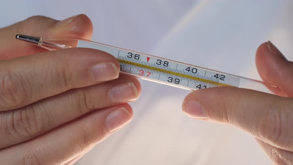 Female Doctor Shows Mercury Thermometer to Camera on Which We See Temperature of 38