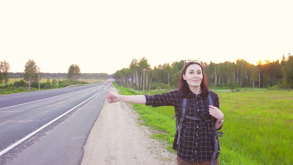 Girl Tourist with a Backpack on the Highway Hitching a Ridethumb Up