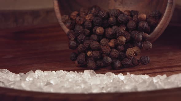 Black Pepper Falling on a Wooden Table with Salt