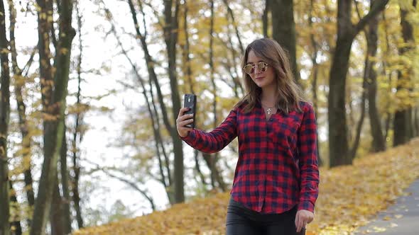 Girl photographed on smartphone in autumn Park exercise outdoors, slow motion