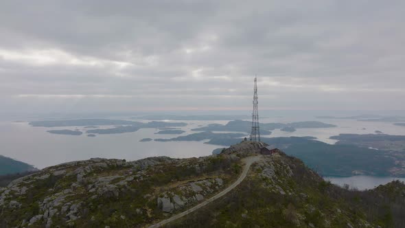 Phone Mast Tower On Top Of Mountain With Island And Calm Waters In The Background. - aerial