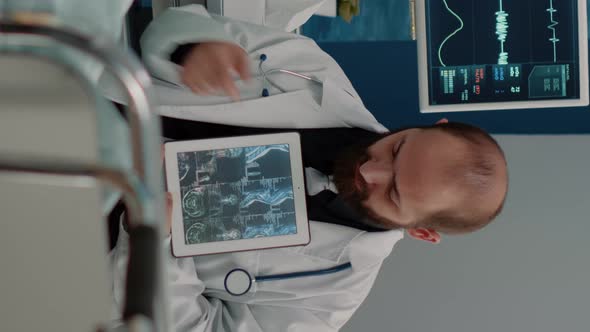 Vertical Video Doctor Showing Osteopathy x Ray on Tablet to Elder Woman