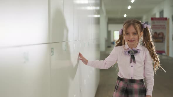 A Little Student Walks Down the School Hallway Near the Lockers.