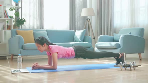 Asian Woman Doing Plank And Watching Online Tutorials On Laptop, Training In Living Room