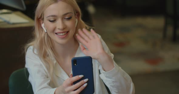 Woman Using Smartphone for Video Call Online at Cafe