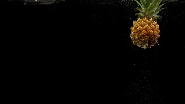 Tropical Fruit Pineapple Under Water with Splash and Air Bubbles on Black Background