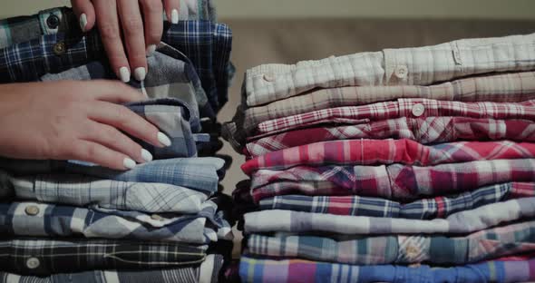 Women's Hands Sort Through a Stack of Men's Shirts