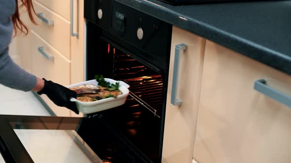Woman in the kitchen prepares a delicious salmon steak in an electric oven