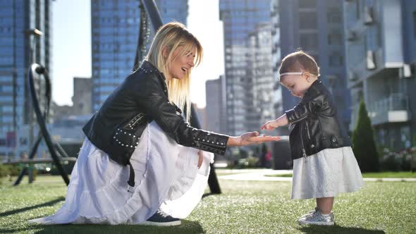 Cute Toddler Girl and Mother Playing in Urban Park