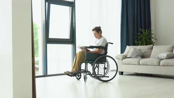 Senior Woman Sitting on the Wheelchair Reading a Book at Home