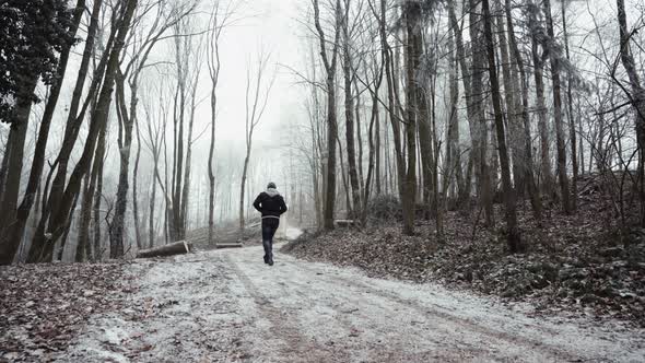 Anonymous man walking on snowy path
