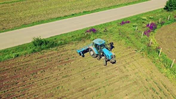 Aerial Shot of Working Tractor on Agricultural Field at Bright Summer Day. 