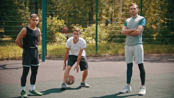 Three Sportsmens Standing on the Basketball Court Outdoors - One Sportsman Doing Keepy-uppies