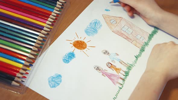 Children's Hands are Drawing a Blue Sky and a Happy Family Closeup