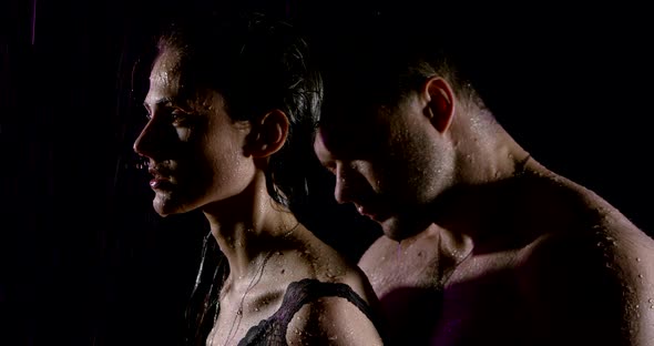 Portrait of a Passionate Beautiful Couple with Bare Shoulders, Which Are Under Heavy Rain on a Black