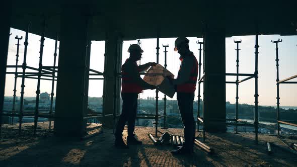 Male Architects Are Discussing Layouts at the Multistory Building Lot alt
