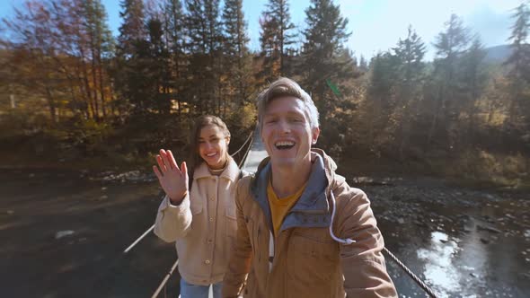 Slow Motion Happy Hikers Couple Walks Together on Wooden Suspension Bridge Hanged Over Mountain