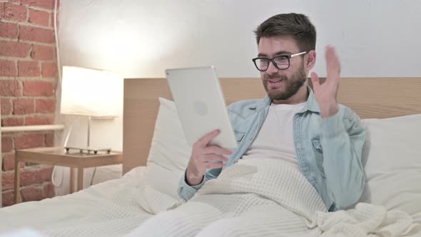 Young Male Designer Doing Video Chat on Tablet in Bed