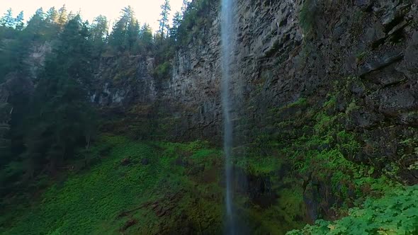 Pan towards an Oregon waterfall with a rock cliff face.