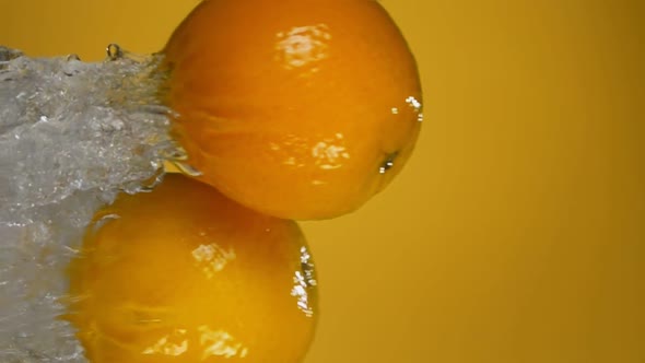 Two Fresh Juicy Oranges are Bouncing Horizontally From the Water with Splashes