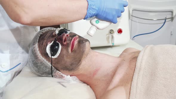 Man Getting Facial Carbon Peeling at Beauty Clinic By Professional Cosmetologist