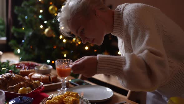 Happy Young Woman Preparing Christmas Dinner Table at Home for Family Party Sprinkles Boiled Corn