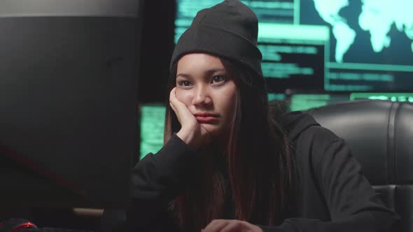 Bored Young Asian Woman Hacker Using Computer Hacking, Code On Multiple Computer Screens