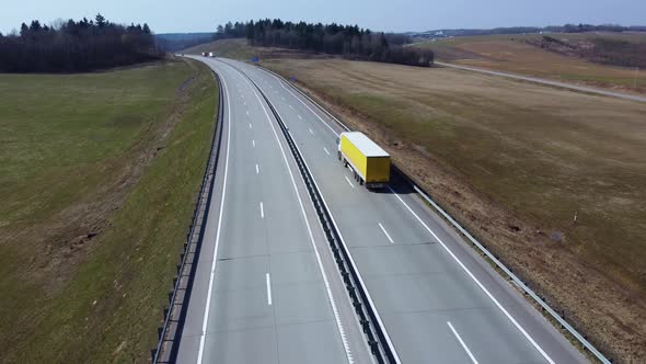 Aerial view of white semi truck with yellow cargo trailer, that moves on the highway