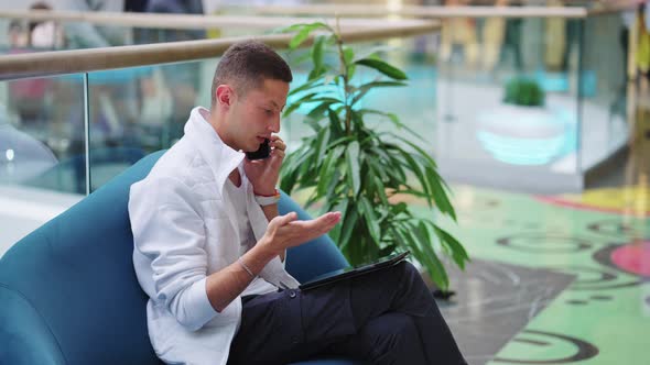 Businessman Talking on Phone in Mall