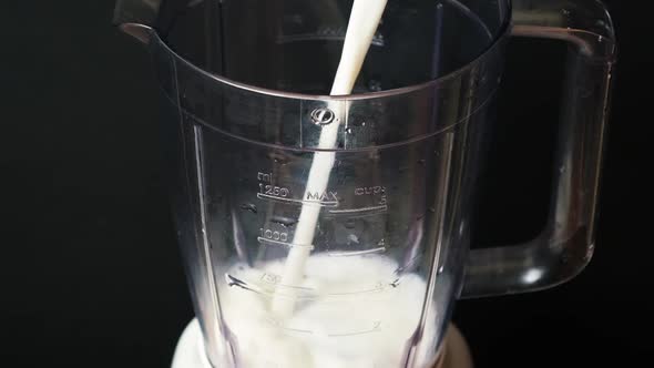 The Process of Pouring Milk Into the Bowl of a Blender for Making a Milkshake